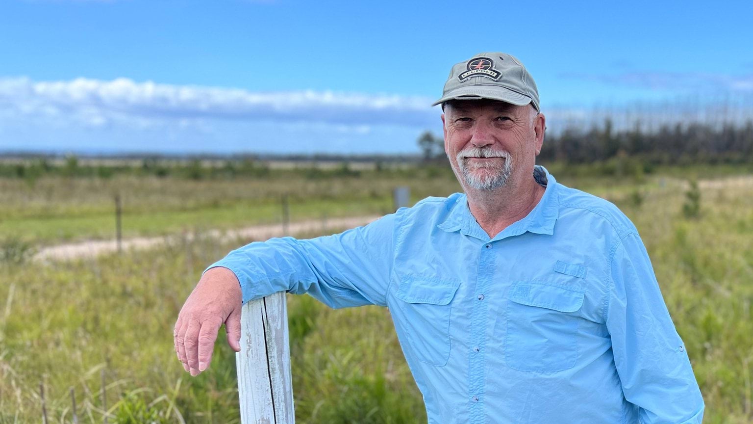 Mallacoota Gun Club, Treasurer, Dave Whittle Mallacoota Gun Club, Treasurer, Dave Whittle wearing a blue shirt and leaning on a fence post in an outdoor field setting