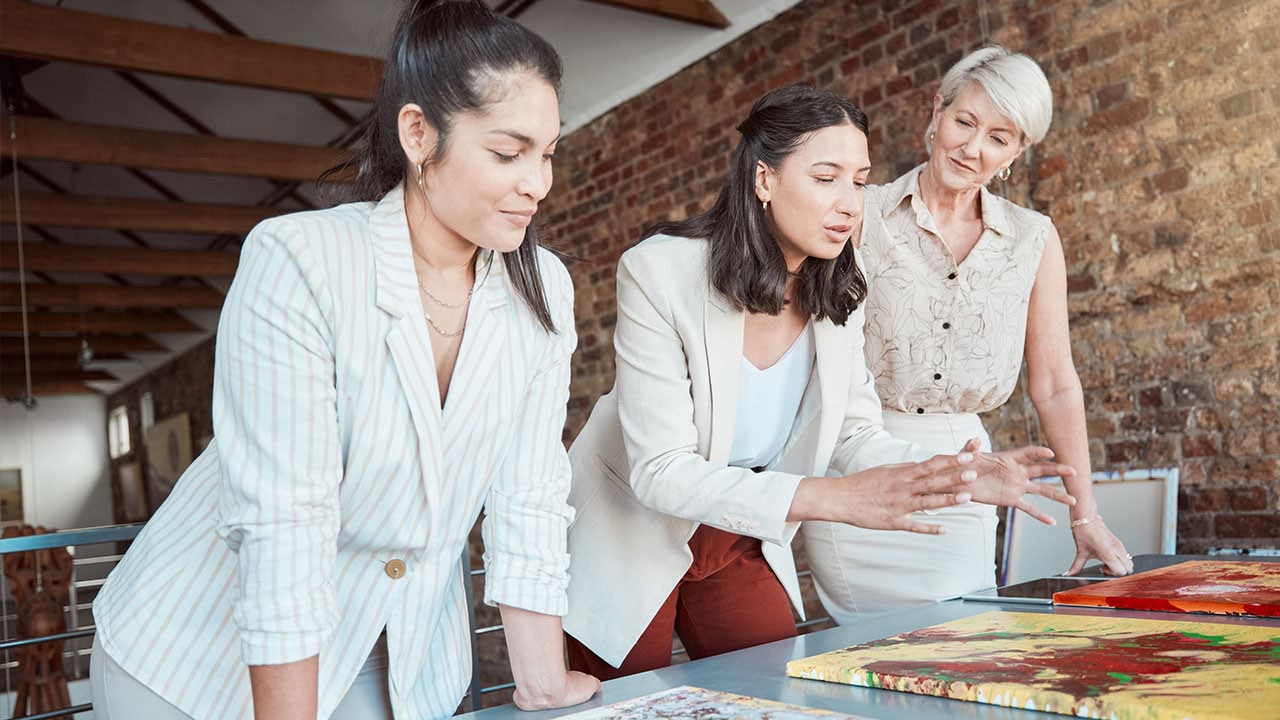 Three people looking at artwork together