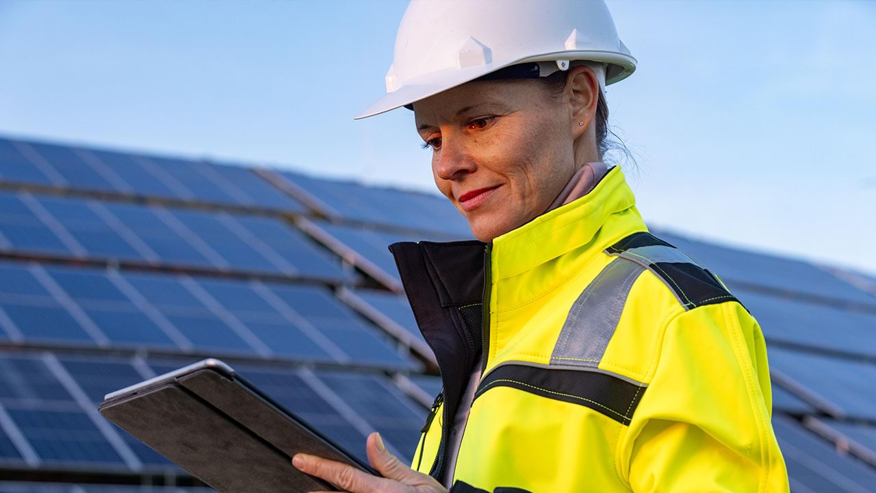 Person with handheld device in front of solar panels