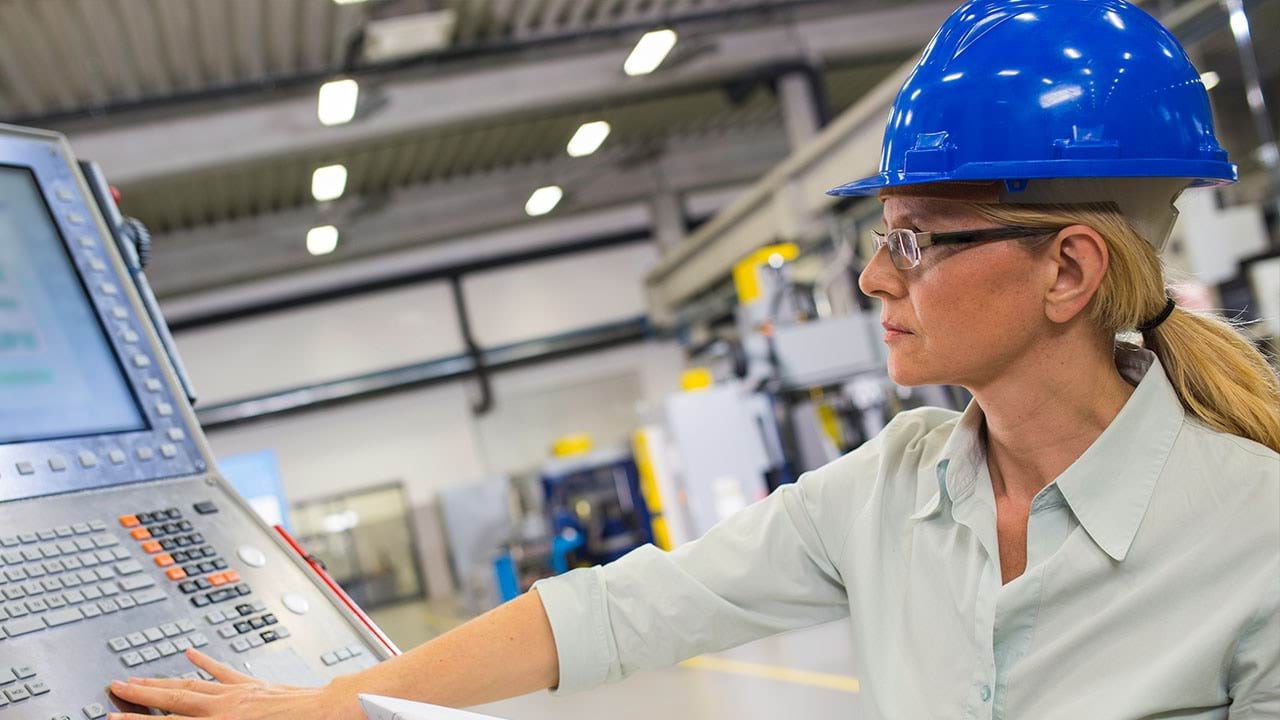 Person programing a machine in manufacturing setting