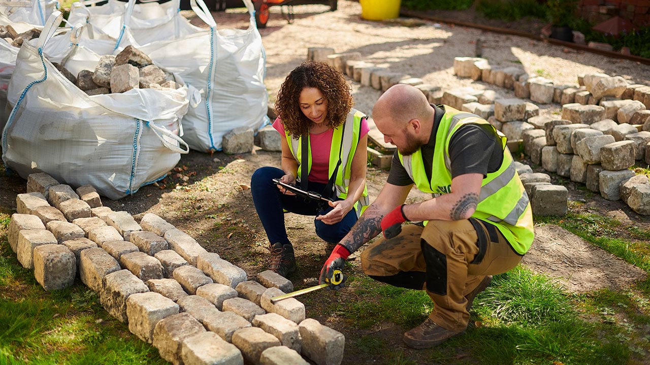 Two people working on paving in garden setting