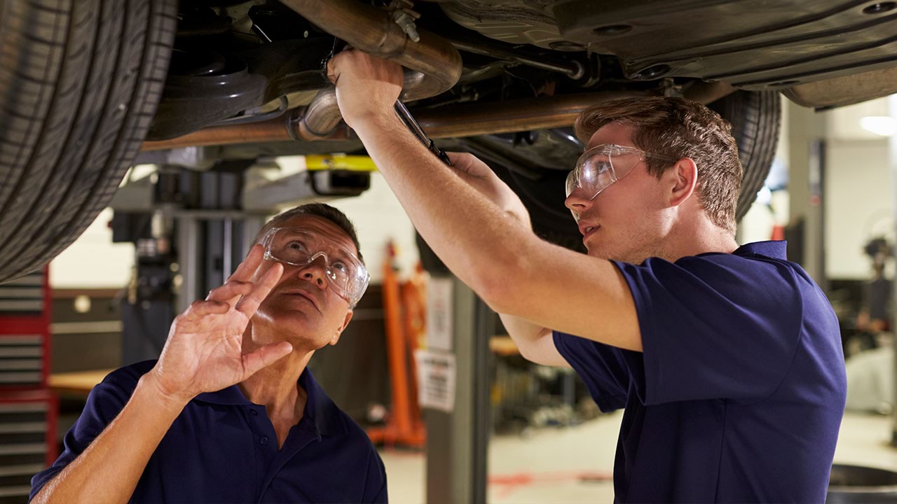 Two people working under a car