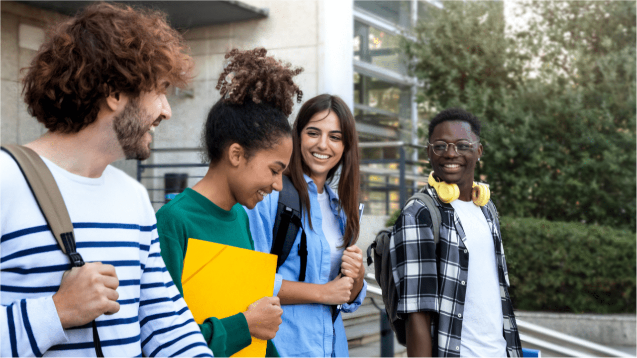 Four students smiling and walking on campus.