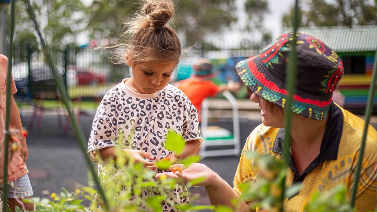 Educator working with child in garden setting