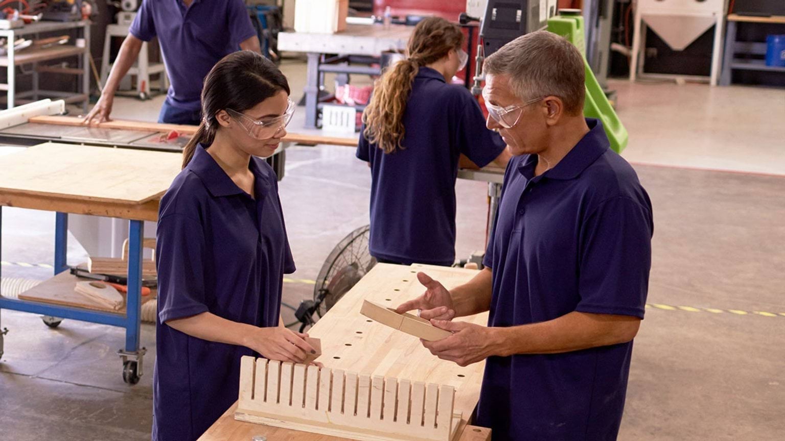 Student learning woodworking with teacher