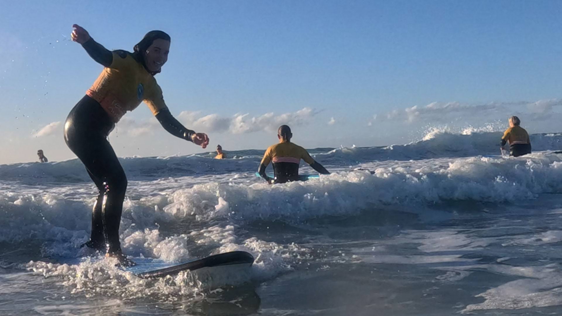 Mallacoota residents surfing in the ocean on their boards with waves out in the sun