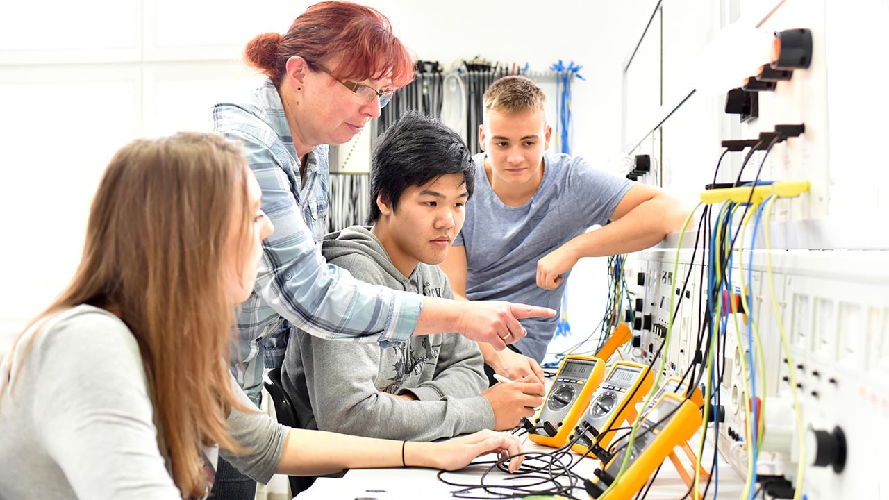 trainer instructing students in electrotechnology lab