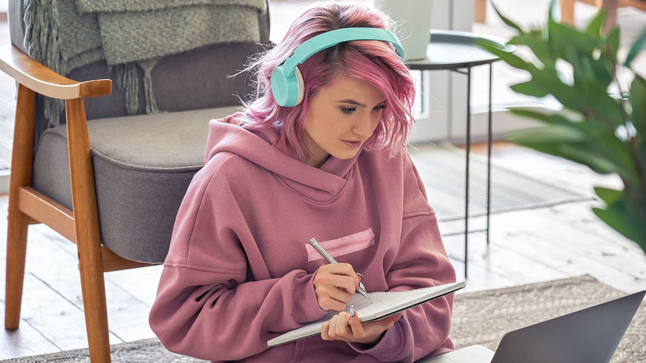 Student wear headphones using a notepad and laptop