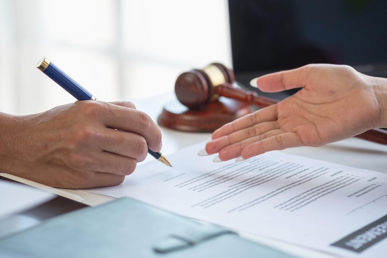 Two people at a desk looking at legal documents with a gavel in sight