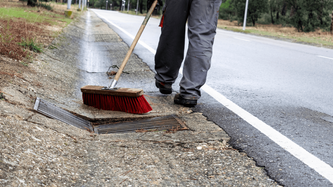 A person brushes water into a drain