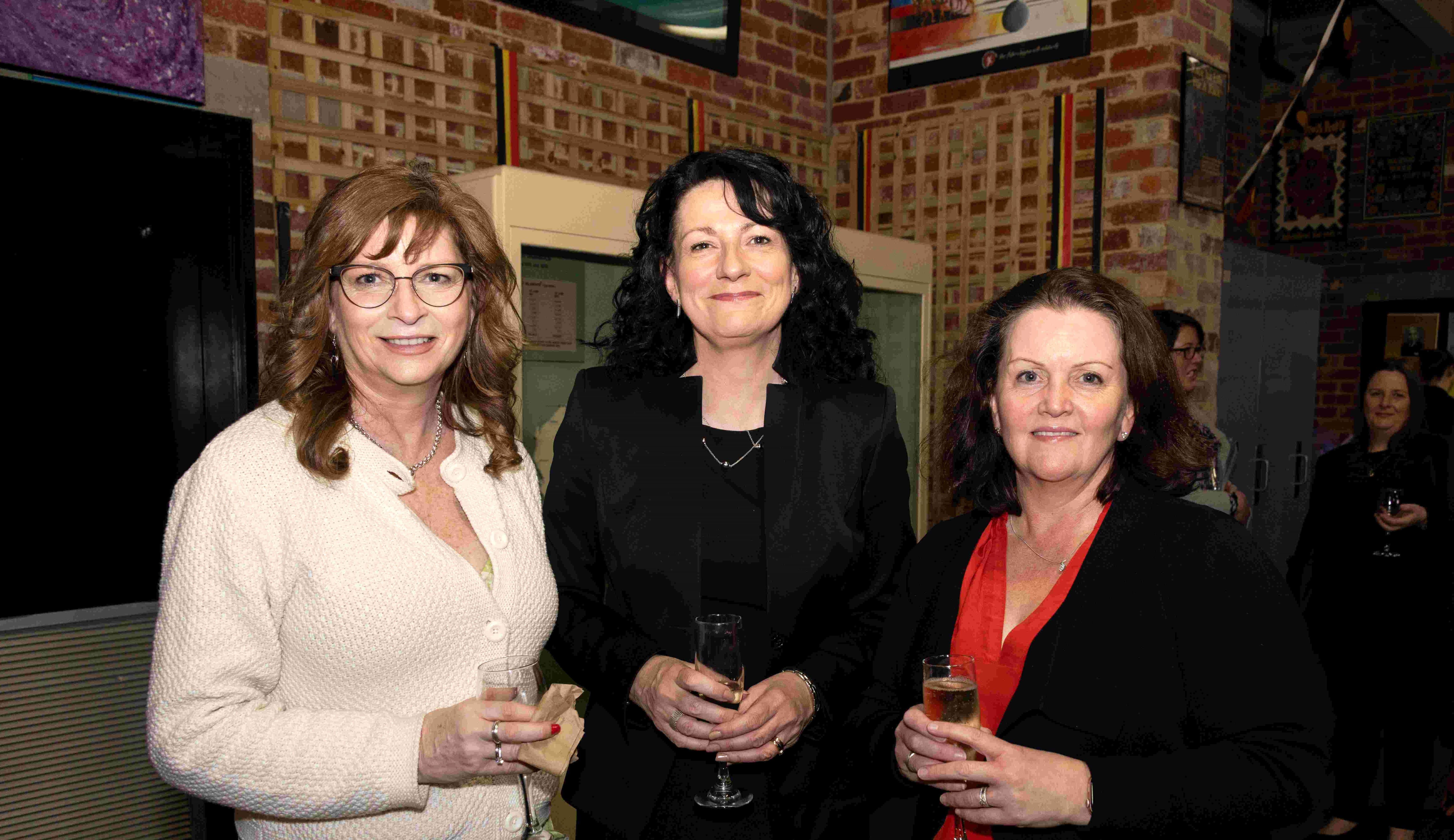 Three people smiling at awards ceremony