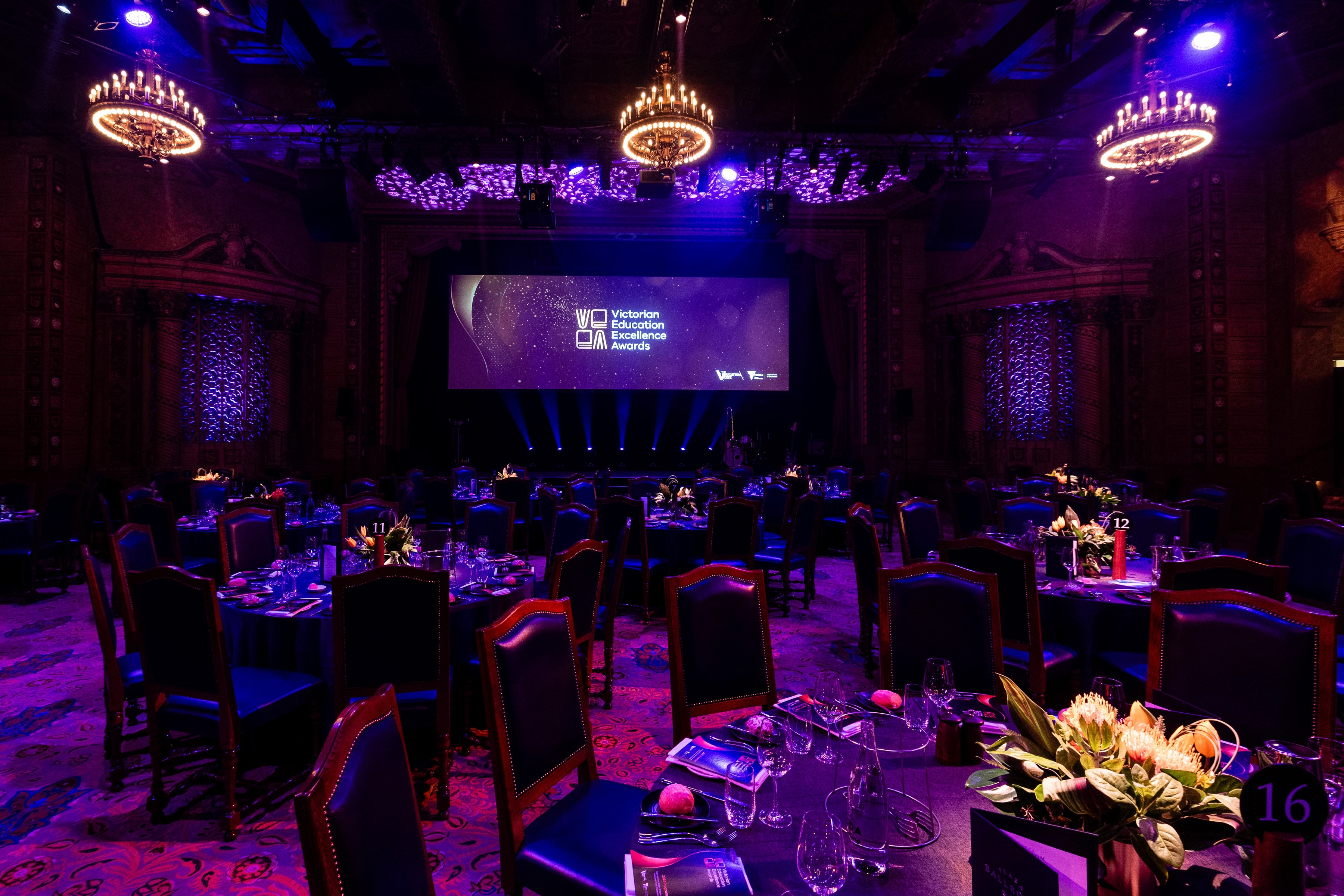 Ballroom with tables, chairs and place settings with purple lighting