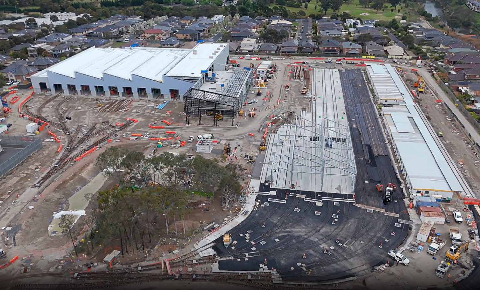 Construction site of Maidstone tram maintenance facility with a large structure under a roof, visible track impressions leading into the building, and laid tracks to the right.