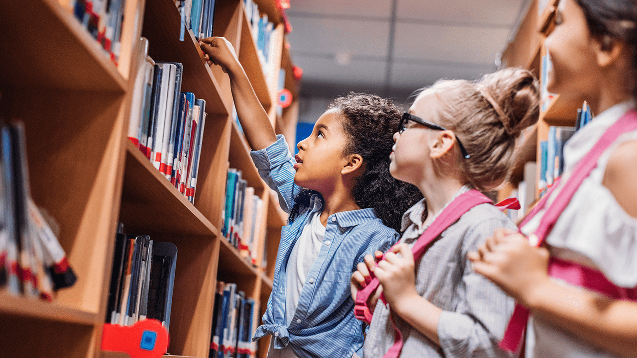 Kids in library looking at Premier's Reading Challenge books.