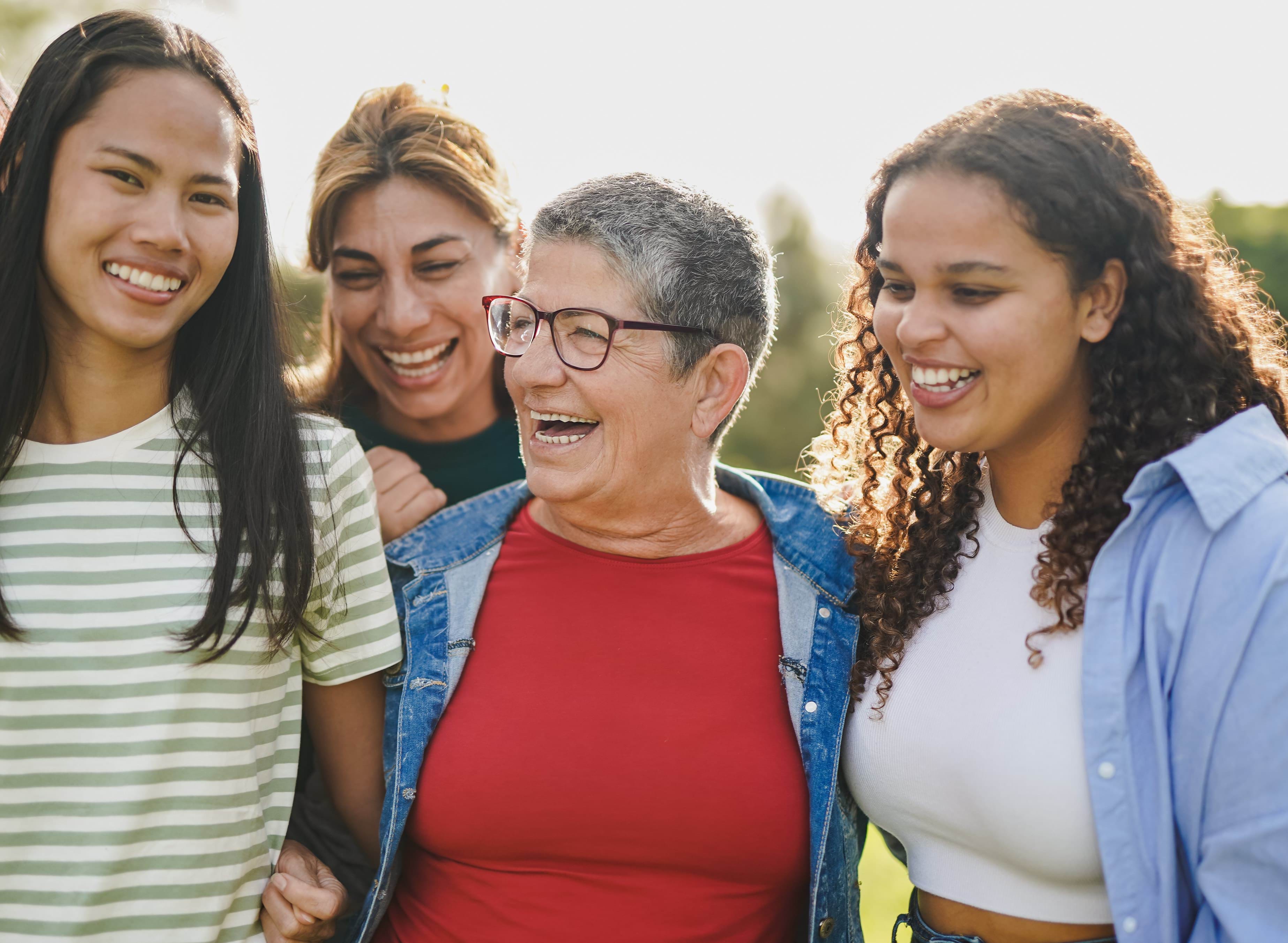 4 women of different ages and races embrace and smile