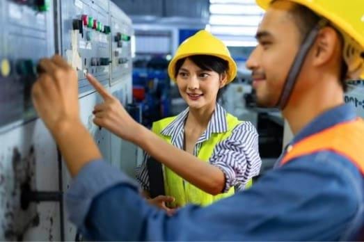 Female and male engineers operating control panel in and industrial setting