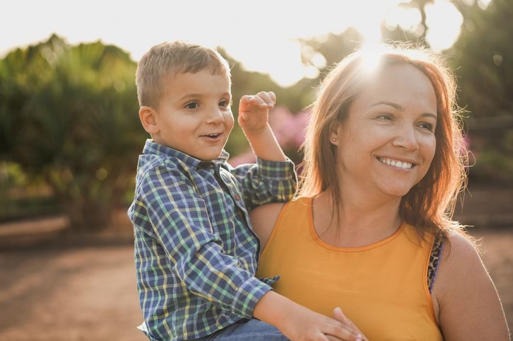 A woman holding a toddler. Both are smiling