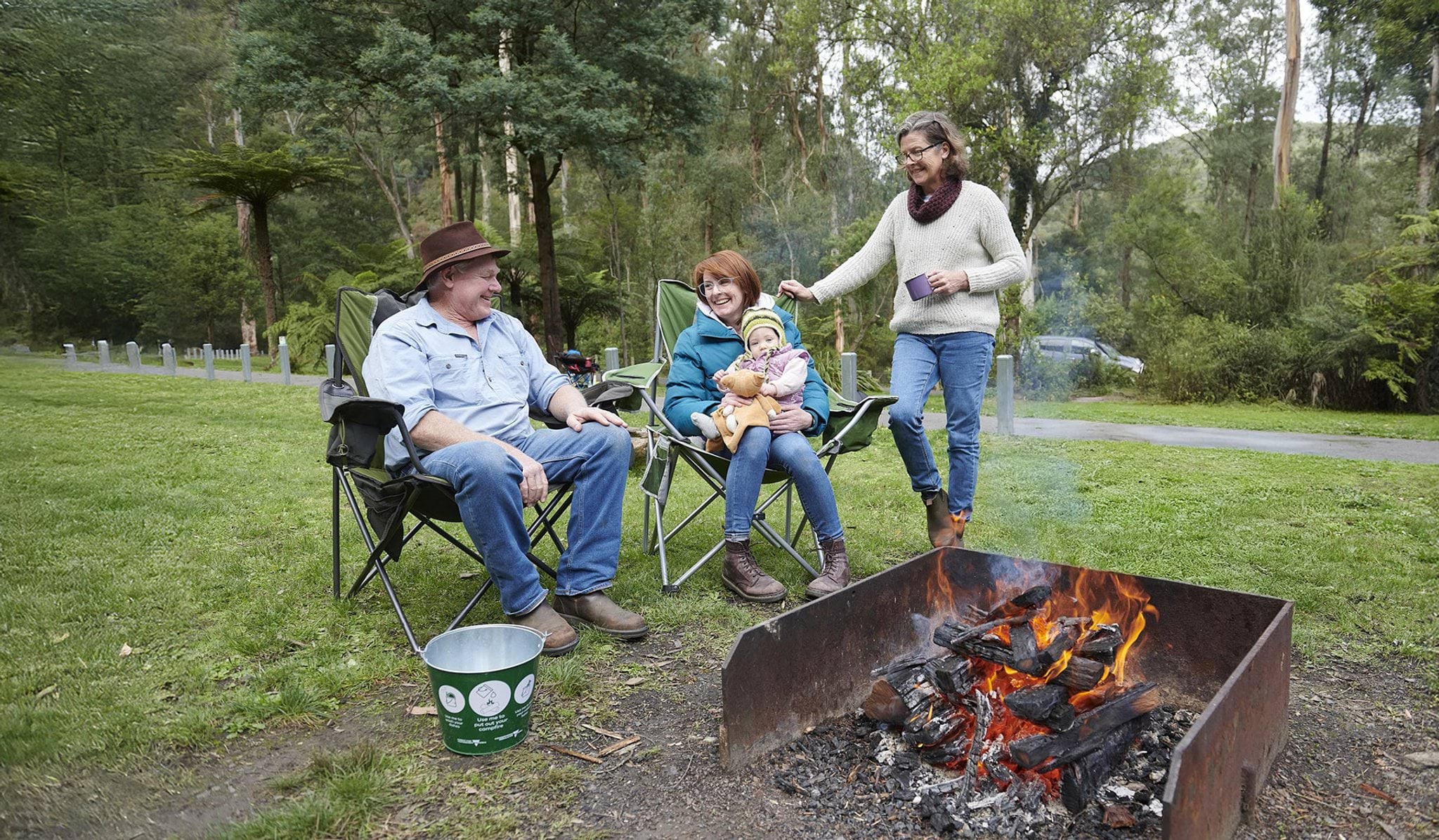 Campers around campfire with safety measures Campers around campfire with safety measures