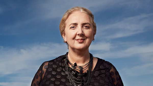 A woman wearing a black dress and smiling at the camera