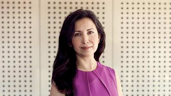 A woman with black hair wearing a purple dress and looking at the camera