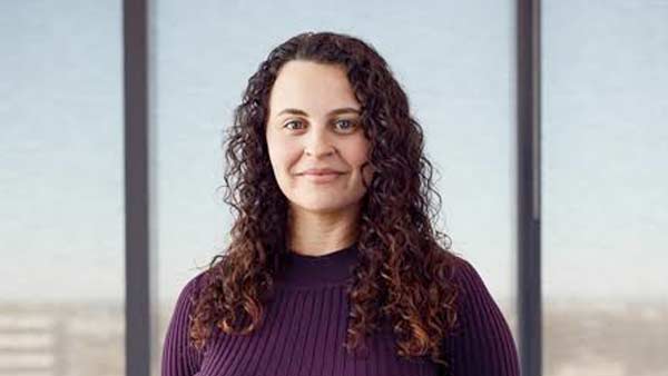 A woman with brown curly hair smiling at the camera