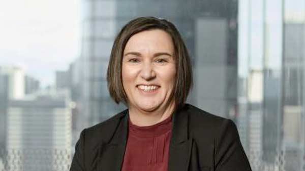 A woman with short hair wearing burgundy top and black blazer