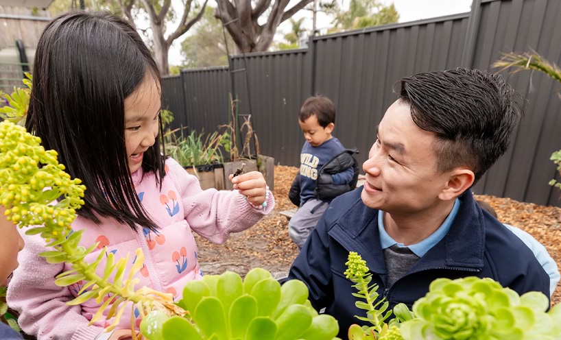 Educator and child talking in centre playground.