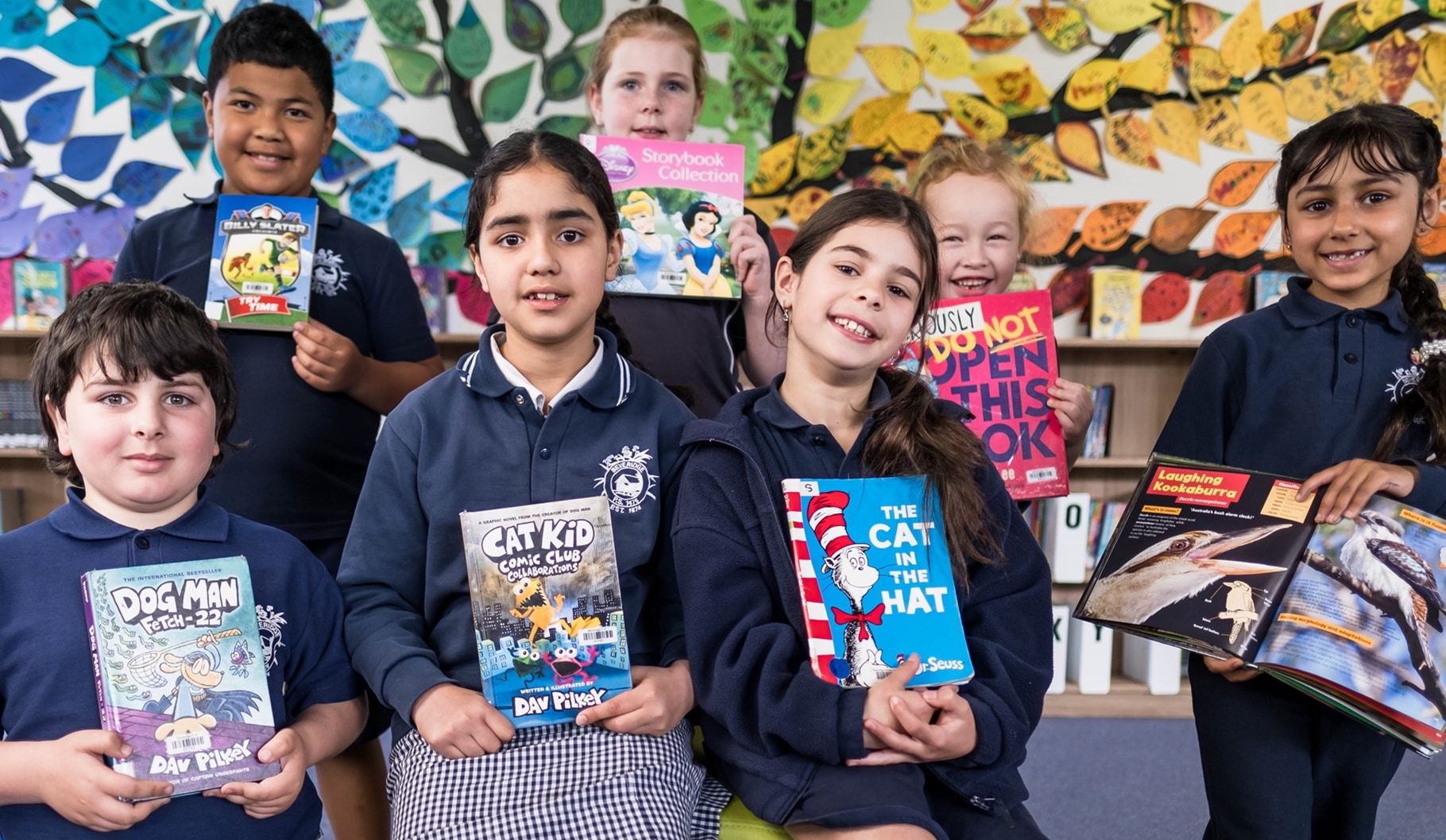 Primary school children holding books in a library.