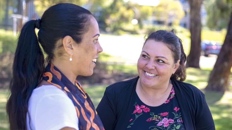 Two smiling women having a converation in a park on a sunny day