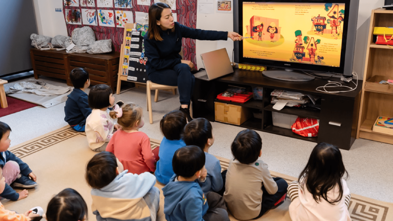 A teacher is showing an image to kids on TV