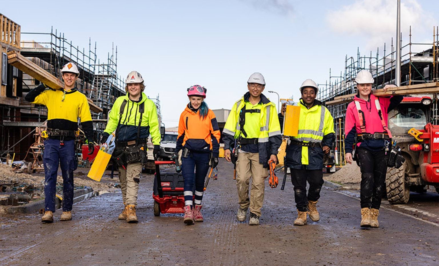 Six young construction workers walking towards the camera