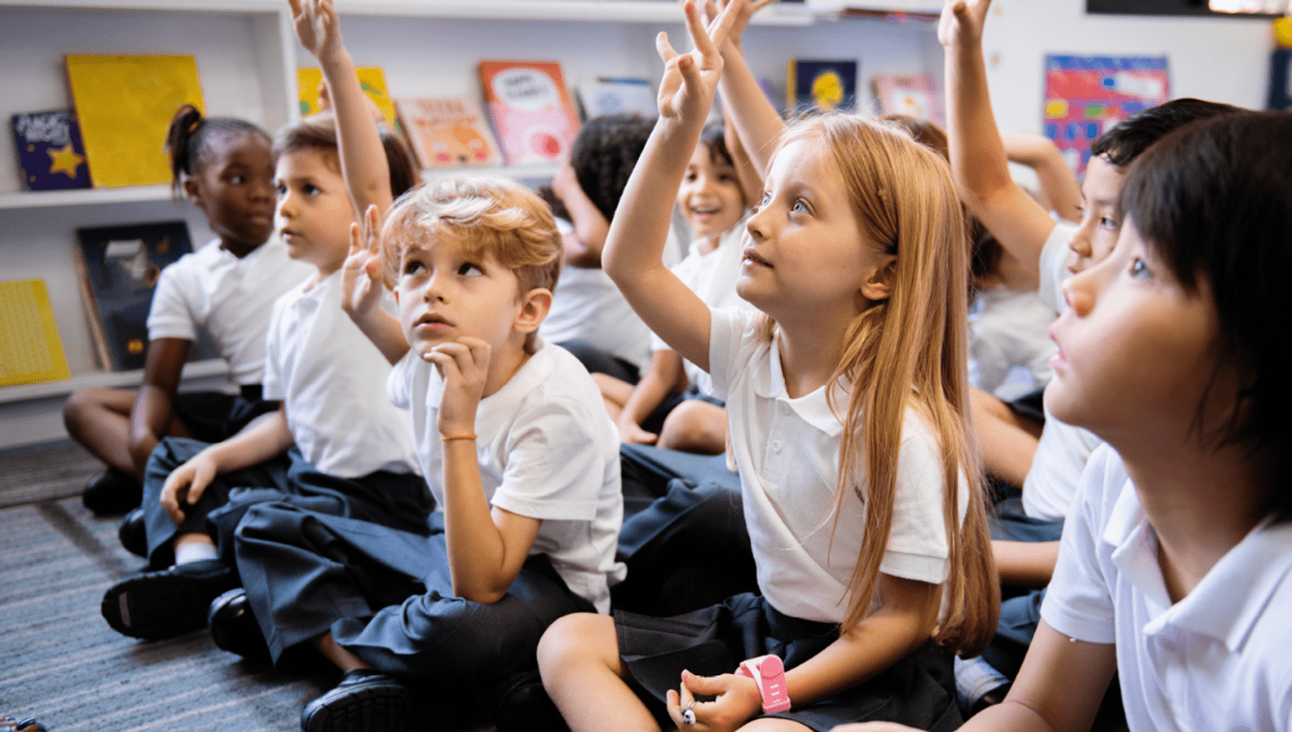 School children sitting on a classroom floor.