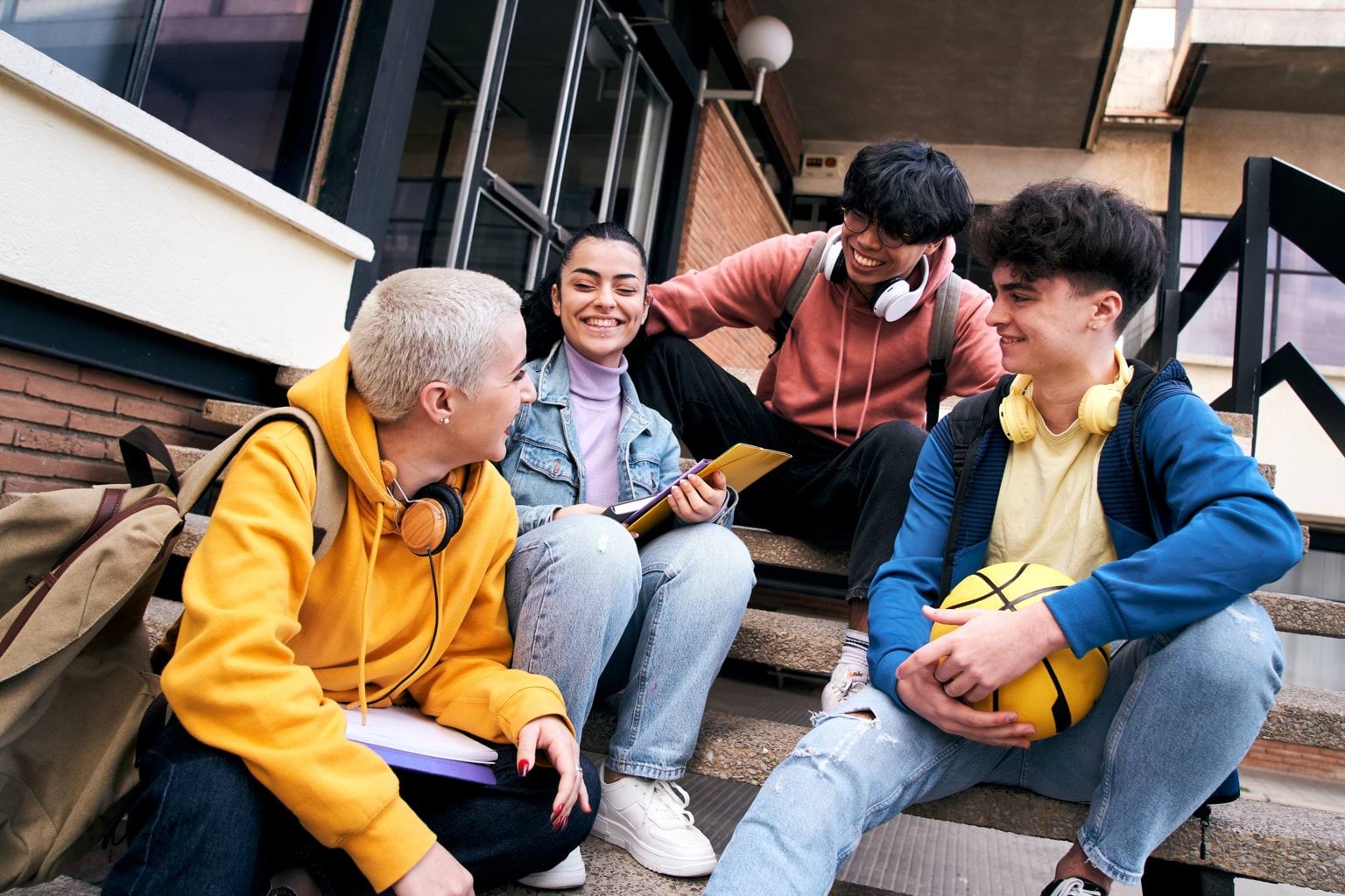 Four students sitting on stairs and smiling.