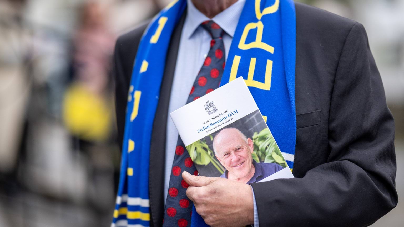 Attendee holding a funeral service program at State Funeral Service for Stefan Romaniw OAM