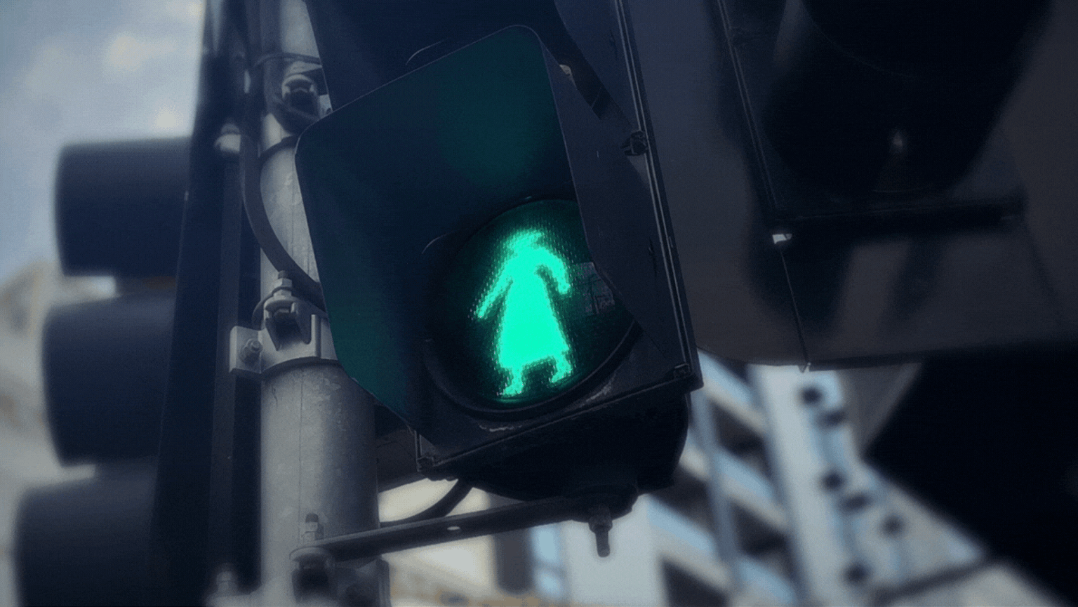 Pedestrian light with a flashing green illuminated outline representing Mary Rogers wearing a hat and dress.