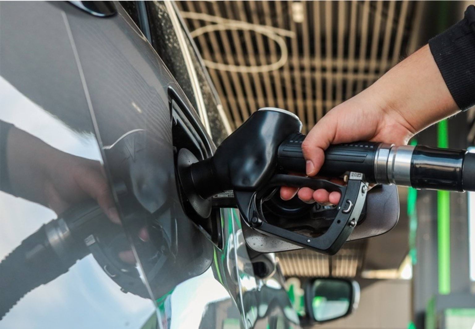 a hand using petrol pump and pumping petrol into a car petrol tank