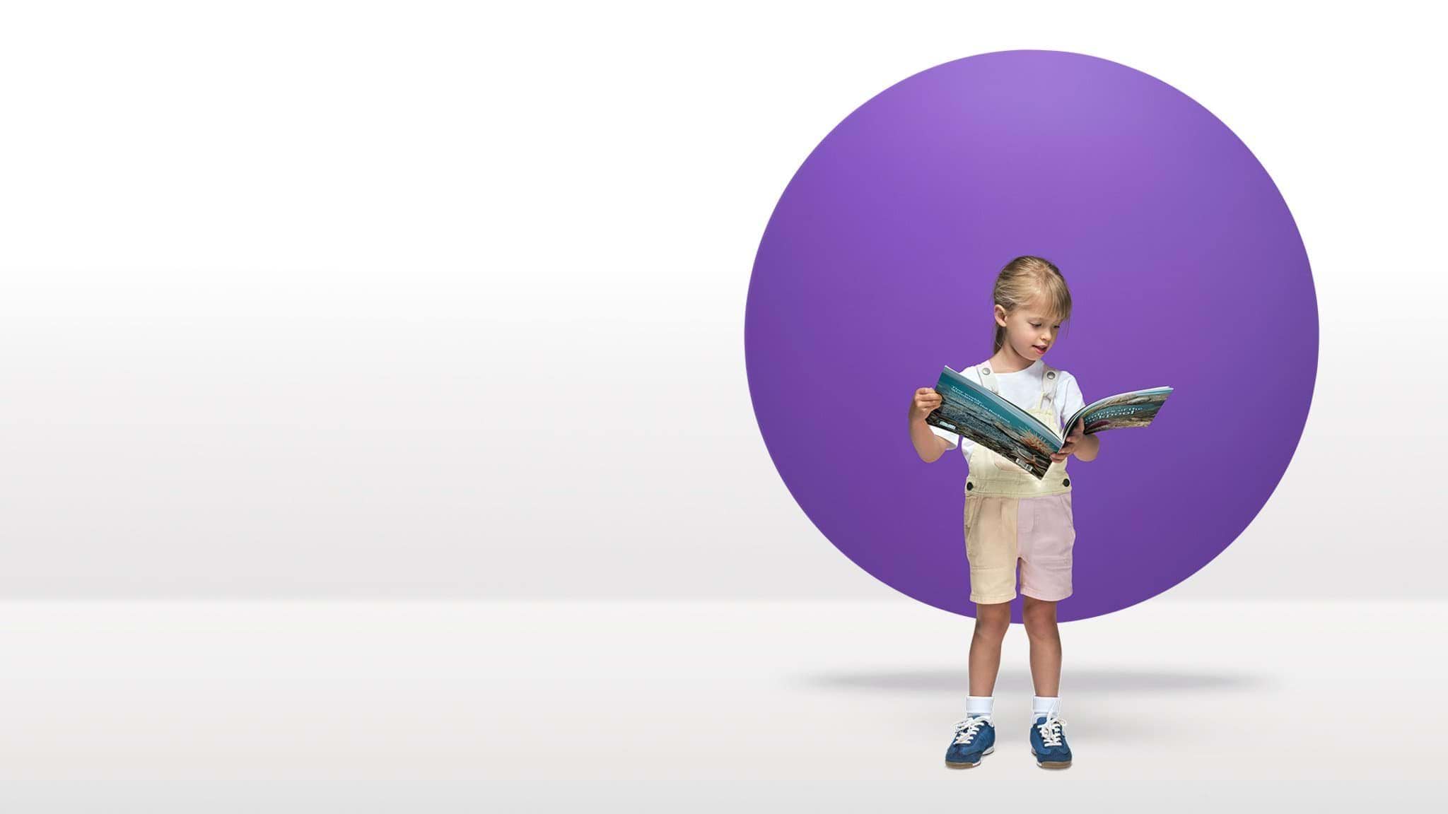 A 3-year-old child reads in front of a purple circle floating in a white space.