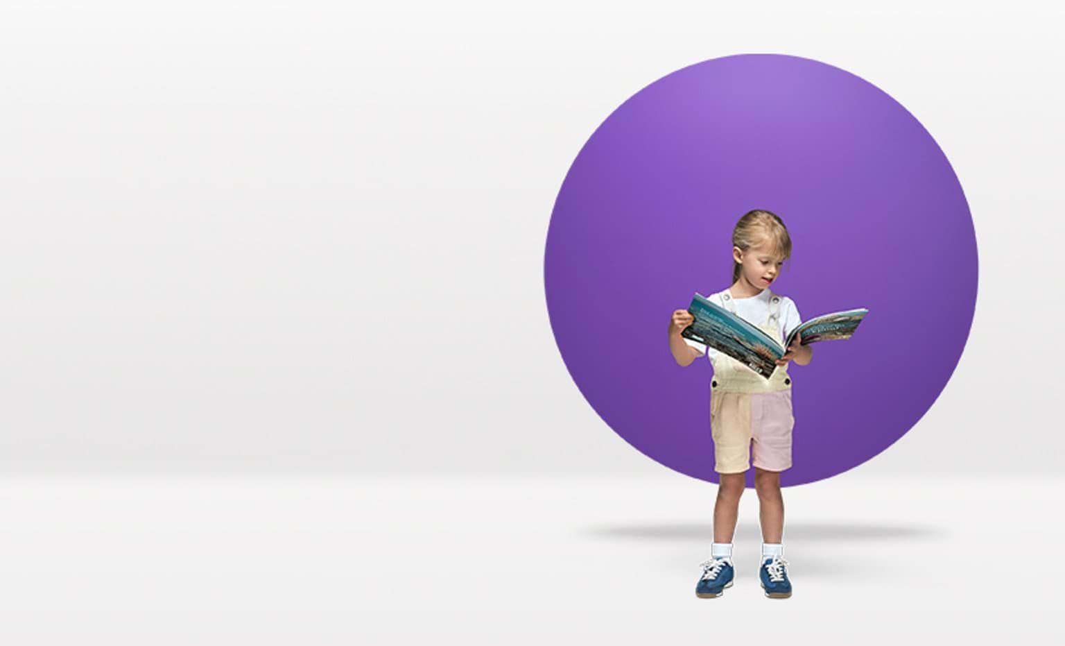 A 3-year-old child reads in front of a purple circle floating in a white space.