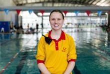 Alicia Farr smiling in front of an indoor swimming pool