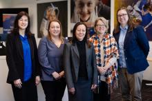 Five staff standing in an office and smiling