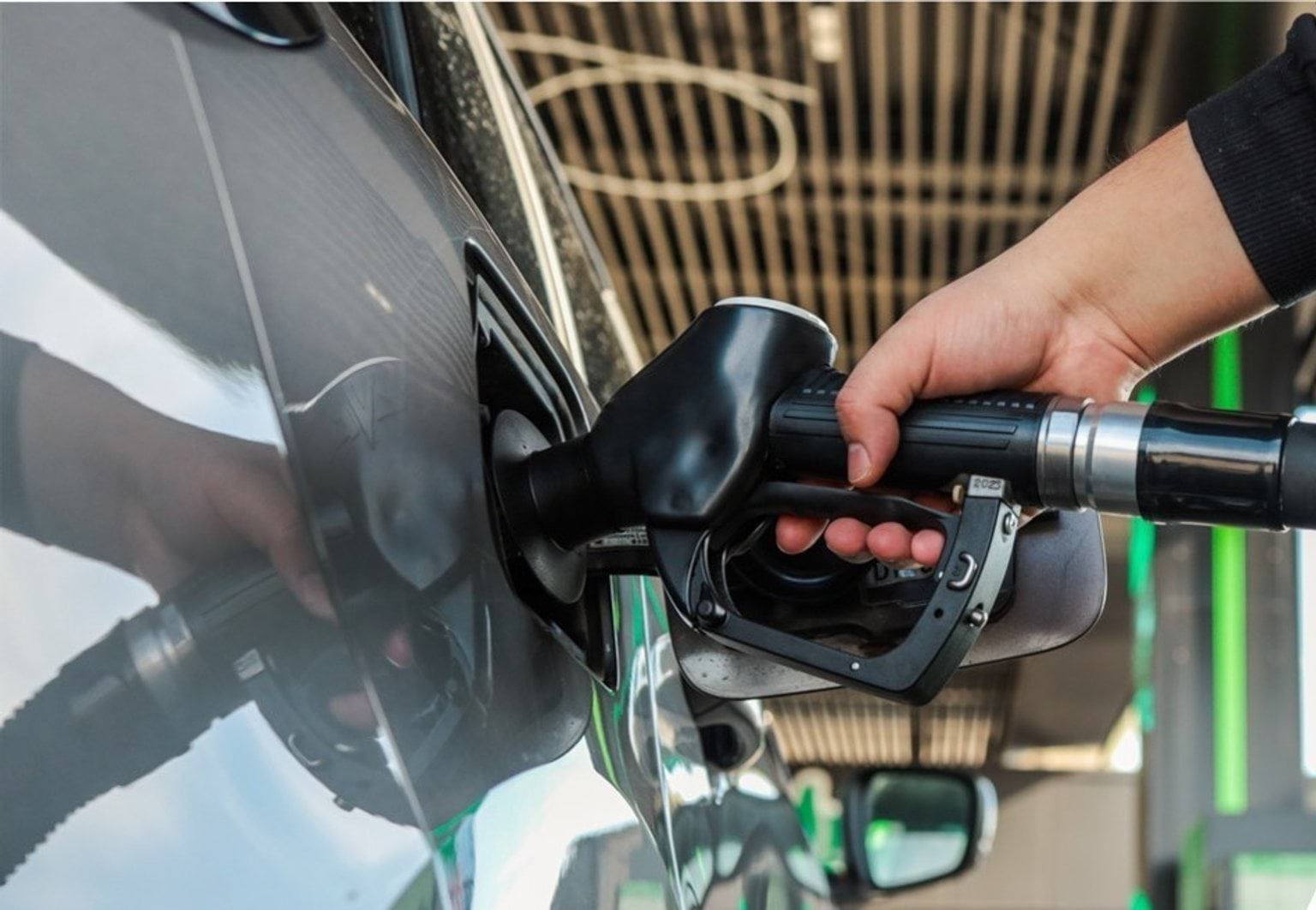 a hand using petrol pump and pumping petrol into a car petrol tank